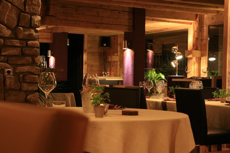 Salle du restaurant Aux Confins des Sens · ambiance chaleureuse bois et pierre, tables dressées aux chandelles